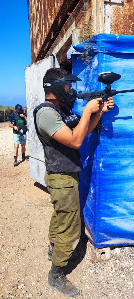 משתתף בפעילות פיינטבול ליד מחסה כחול במתחם